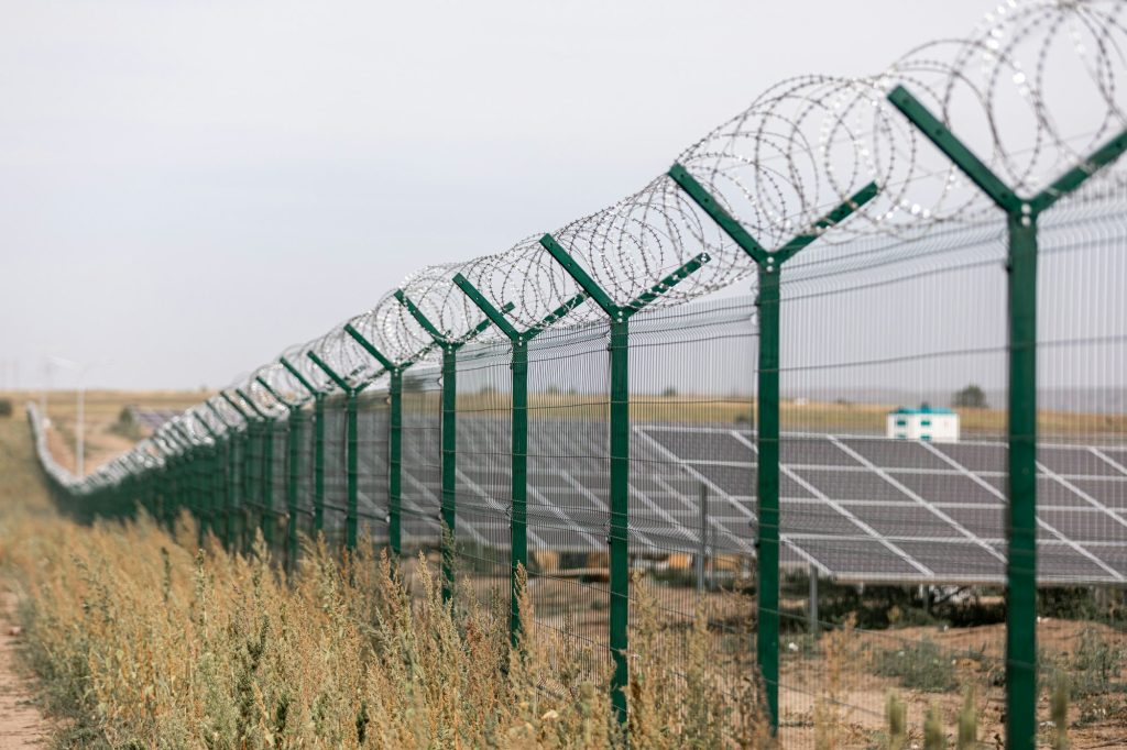 Solar panel in the field fenced in a metal barbed wire. photovoltaic, alternative electricity source